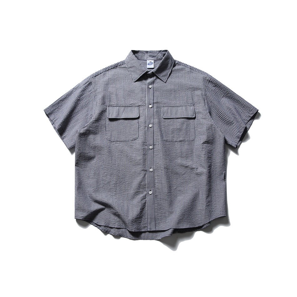Navy and white striped short-sleeve button-up shirt with two flap chest pockets, front view on white background