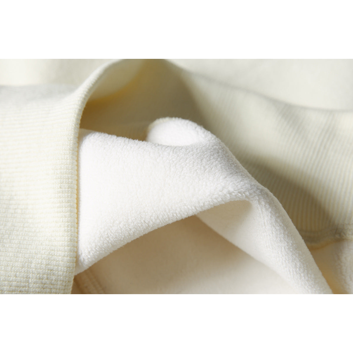 Close-up showing the soft, fuzzy inner surface of an ivory hoodie.