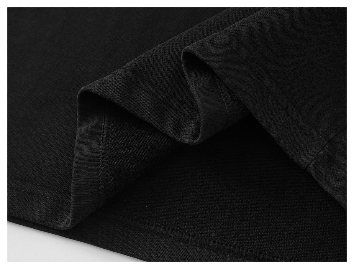 Close-up of the black sweatshirt's folded hem and interior overlock stitching.