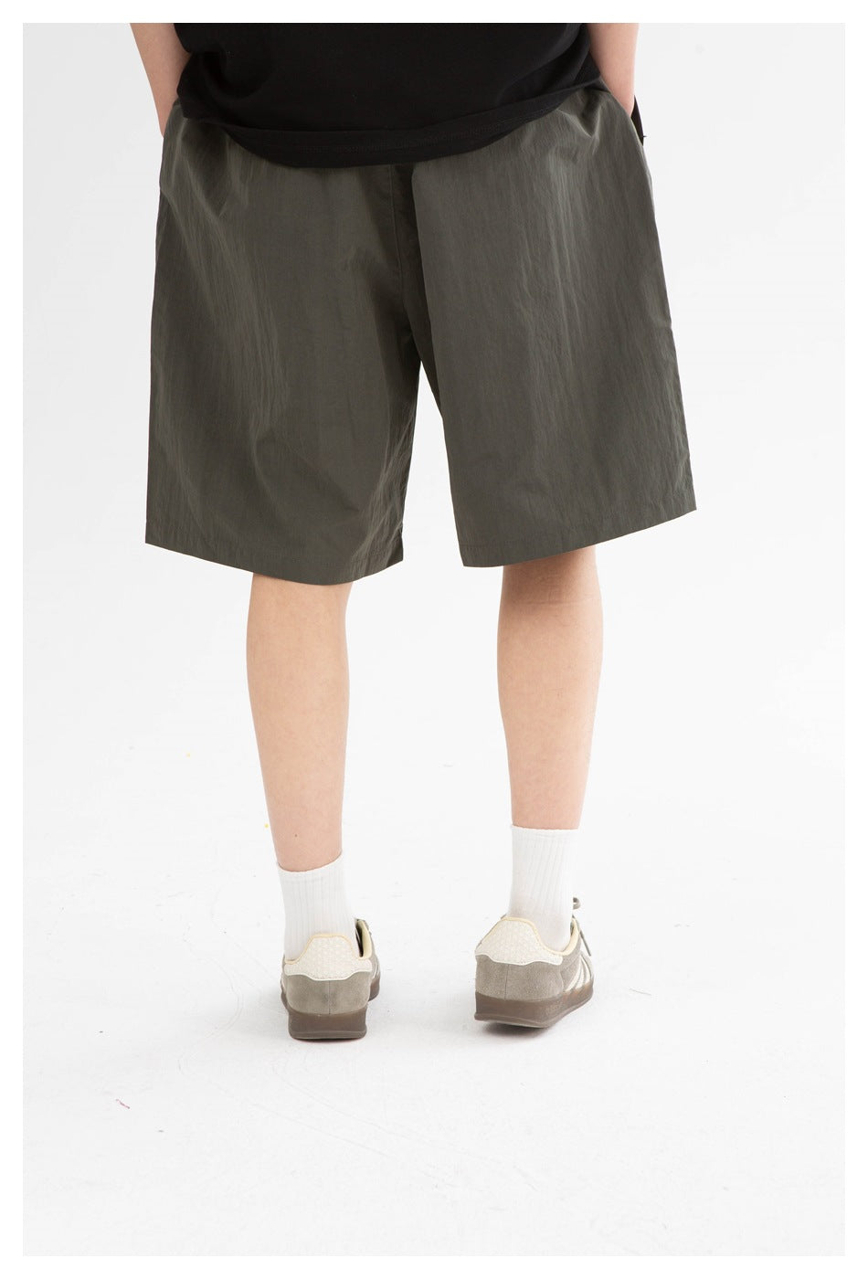 Cropped rear view of a model wearing dark olive knee-length shorts.