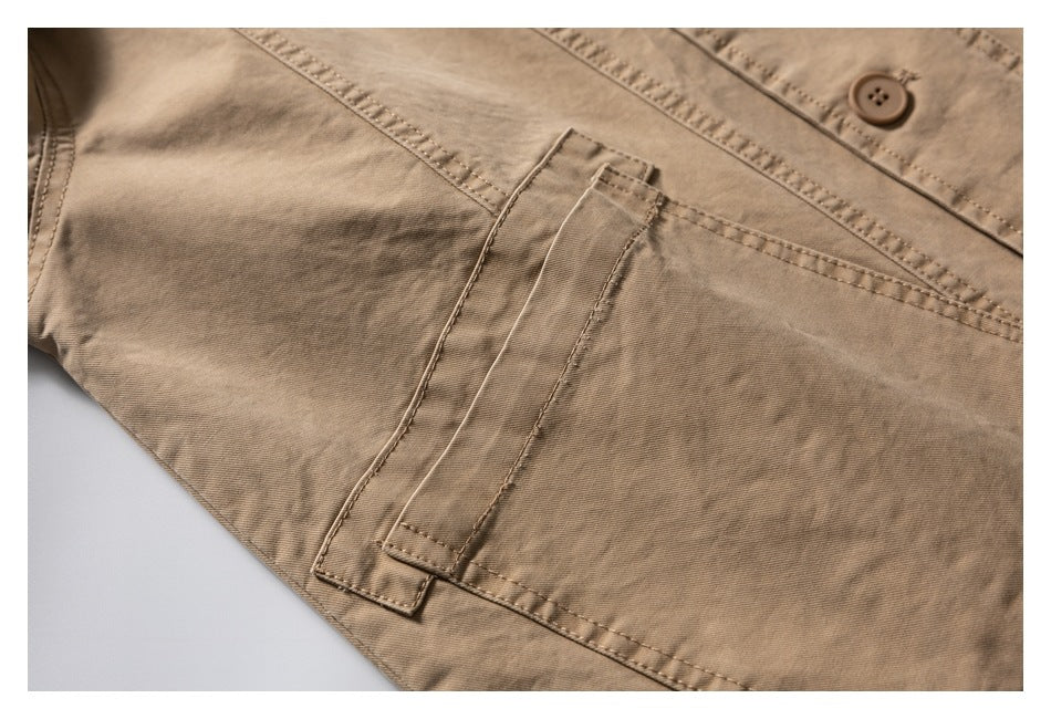 Close-up of a tan jacket showing a stitched front pocket flap and matching button.