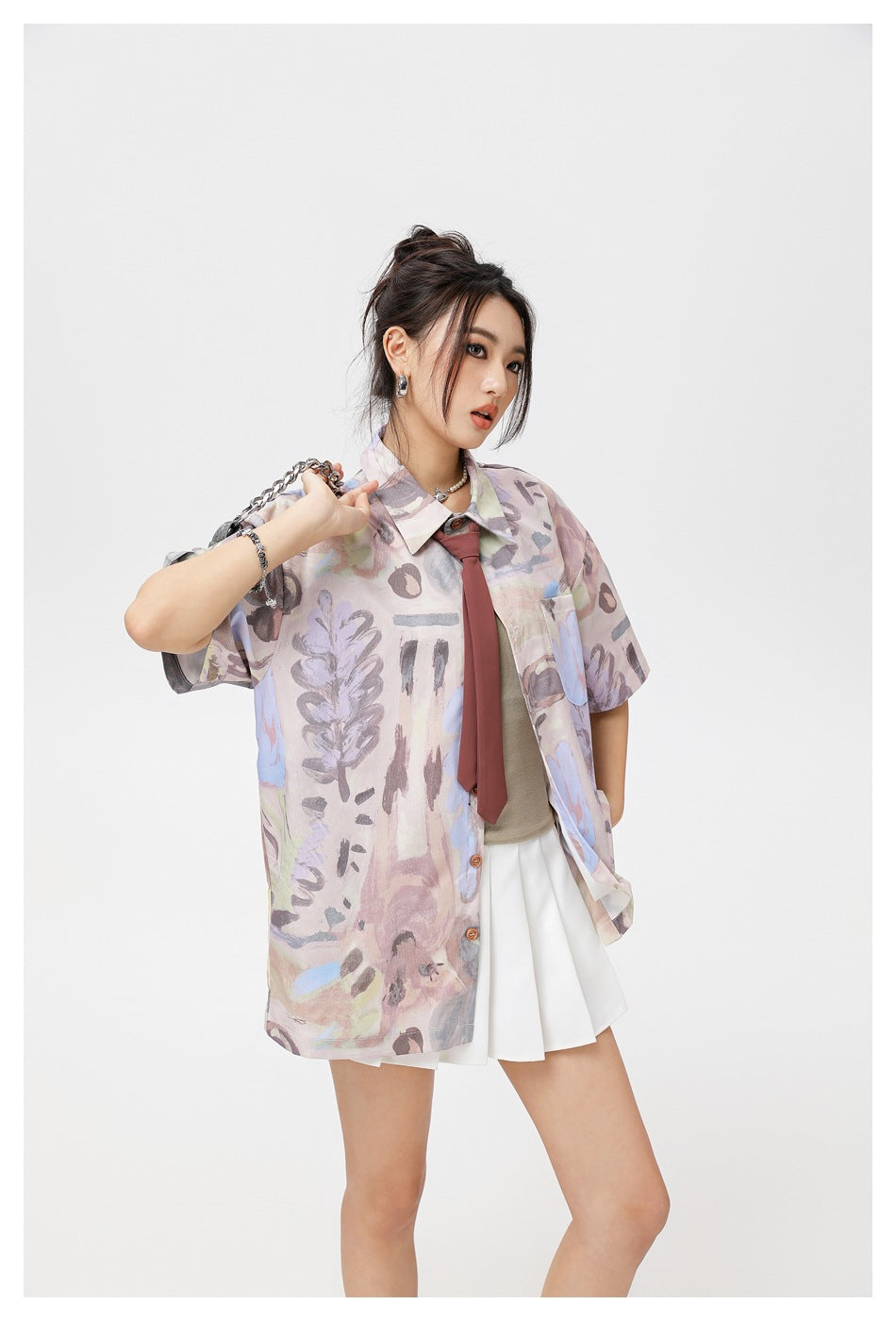Model wearing an oversized pastel abstract-print short-sleeve button-up shirt with a chest pocket, burgundy tie and white
