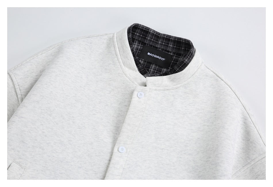 Close-up of a light gray jacket's stand collar and upper button front, with plaid lining visible inside the collar.