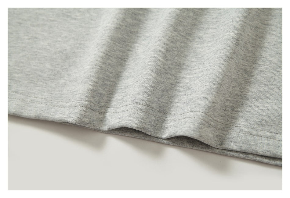Close-up of the stitched bottom hem on heather-gray shirt fabric.
