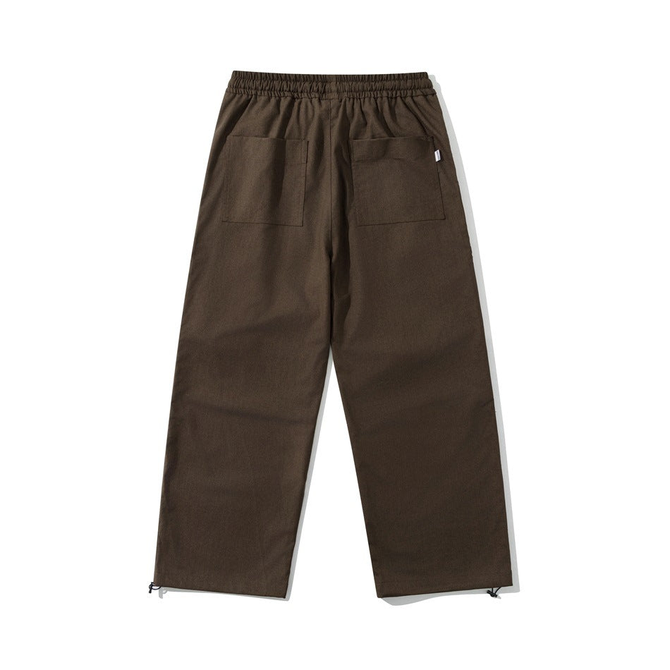 Back view of dark brown loose-fit pants with an elastic waistband, two patch pockets, and adjustable ankle hems.