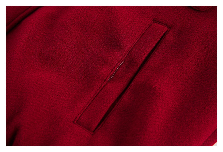 Close-up of a narrow welt pocket on burgundy coat fabric.