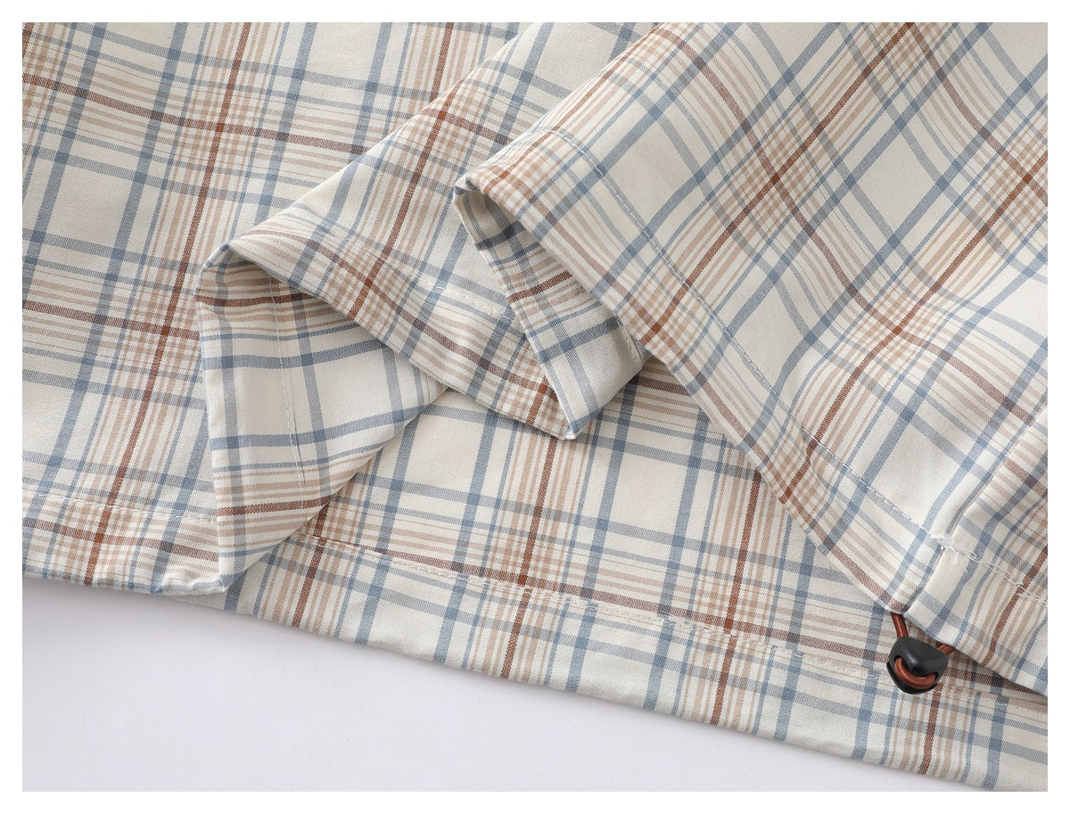 Close-up of the plaid shirt's folded fabric, stitching, and a small brown loop detail.