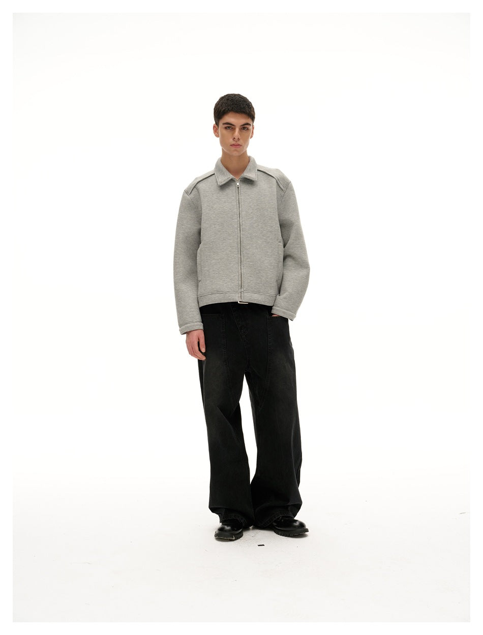 Model wearing a gray zip-front collared jacket with black wide-leg jeans and black boots, front view
