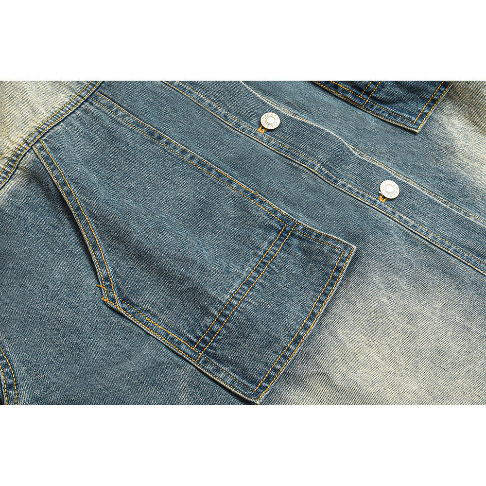 Close-up of the denim jacket’s front pocket, diagonal panel seams, yellow stitching, and metal buttons.