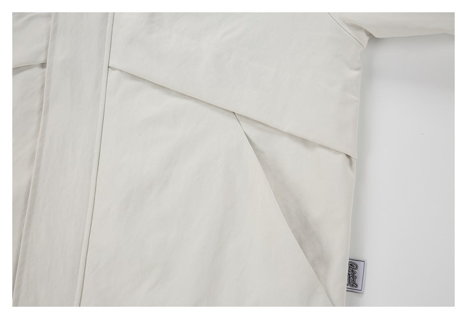 Close-up of the off-white jacket's layered side panels, stitching, and a small sewn label.