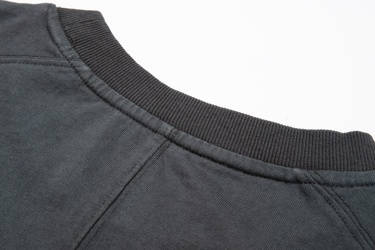 Close-up of a charcoal gray top's crew neckline with a dark ribbed collar and shoulder seams.