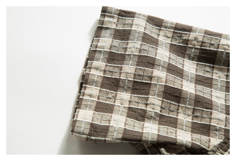 Close-up of a folded edge on a brown, beige, and gray plaid garment.