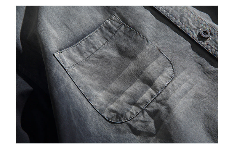 Close-up of a charcoal shirt's chest pocket, stitching, and button placket.