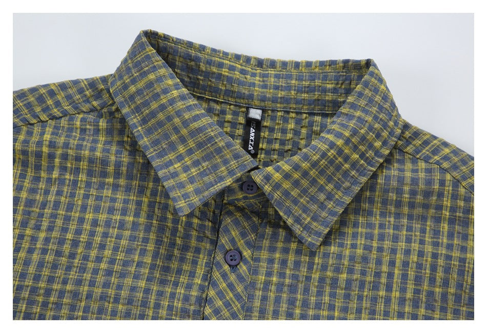 Close-up of a blue-gray and mustard plaid shirt collar, buttons, and sewn-in black neck label.
