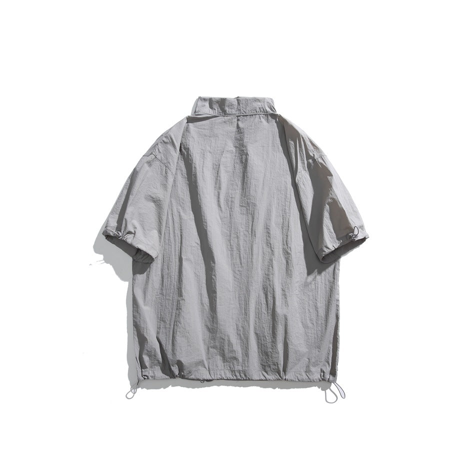 Back view of a light gray short-sleeve jacket laid flat, with adjustable cords at the cuffs and hem.