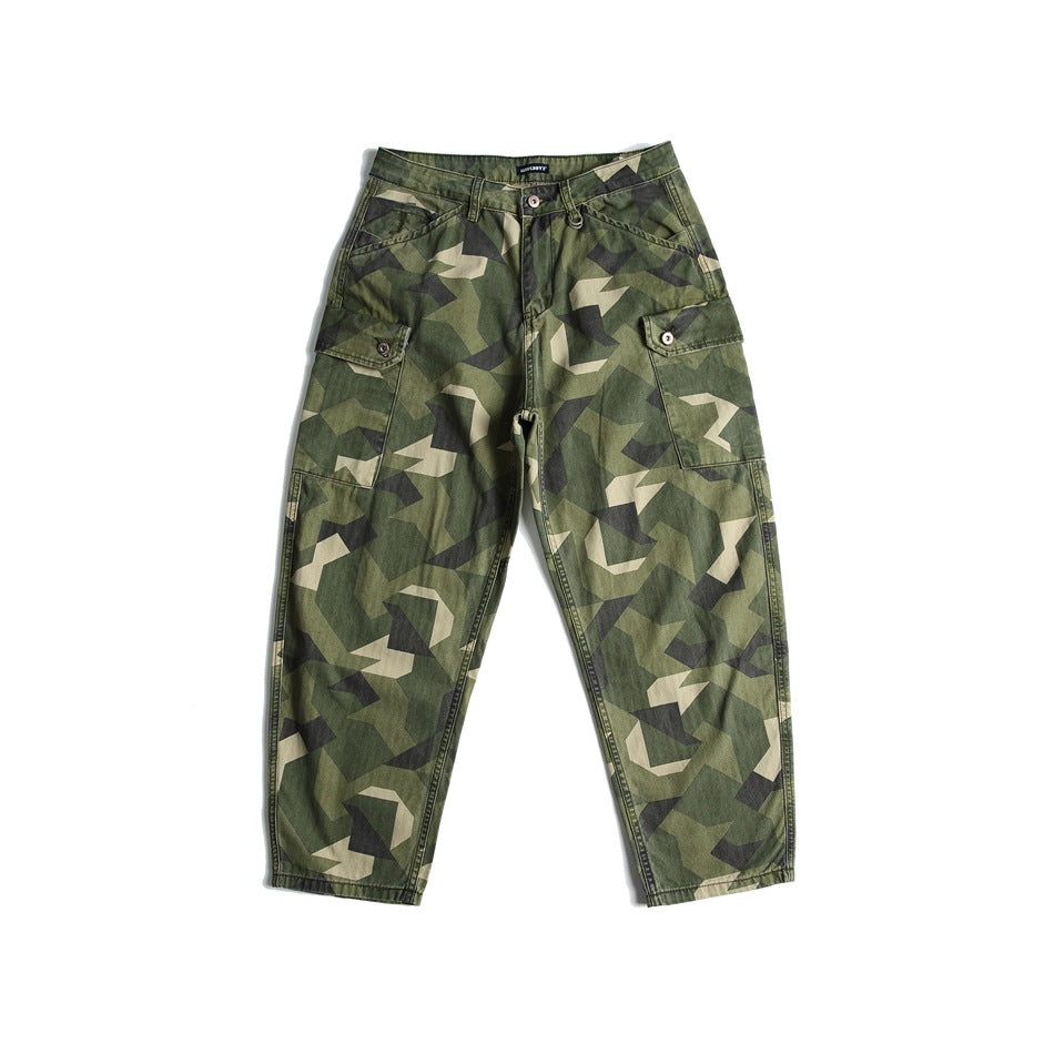 Front view of green geometric camouflage cargo pants with button-flap side pockets on a white background