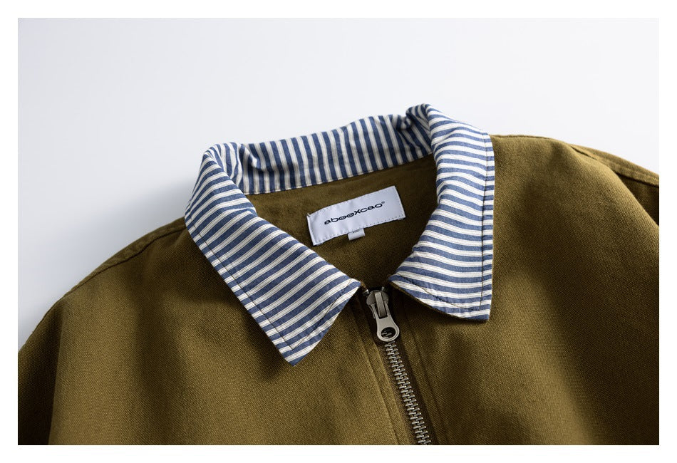 Close-up of an olive-brown jacket with a blue-and-white striped collar, front zipper, and sewn neck label.