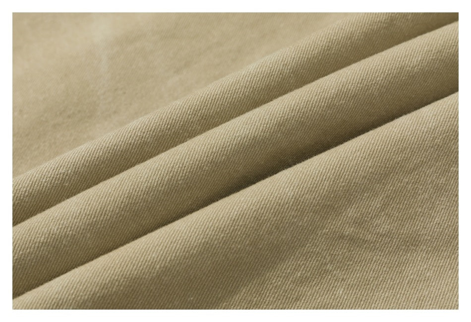 Close-up of tan fabric arranged in folds, showing its fine diagonal weave.