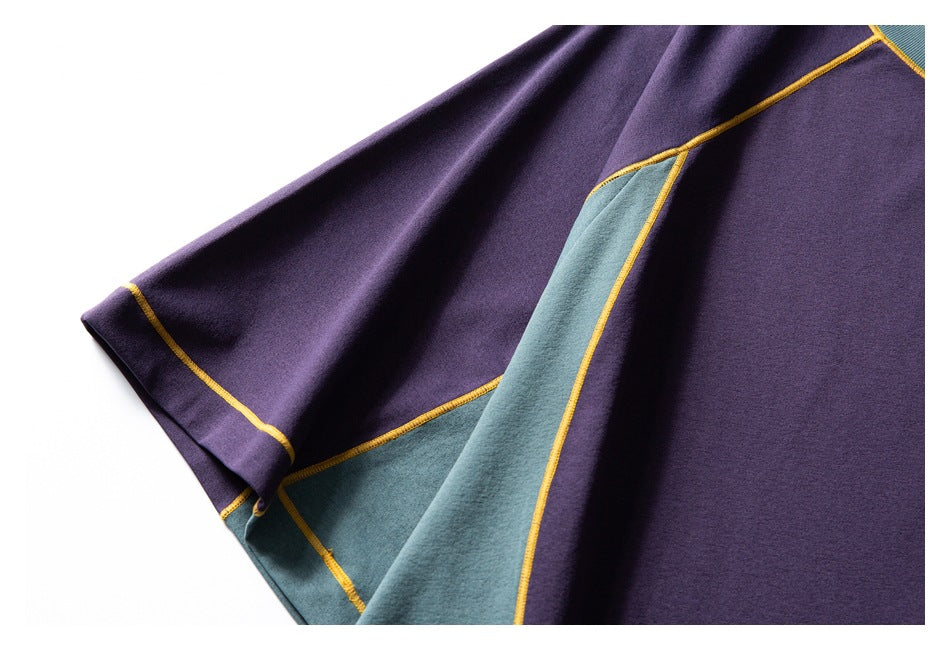 Close-up of a purple garment with a teal panel and mustard-yellow seam stitching.