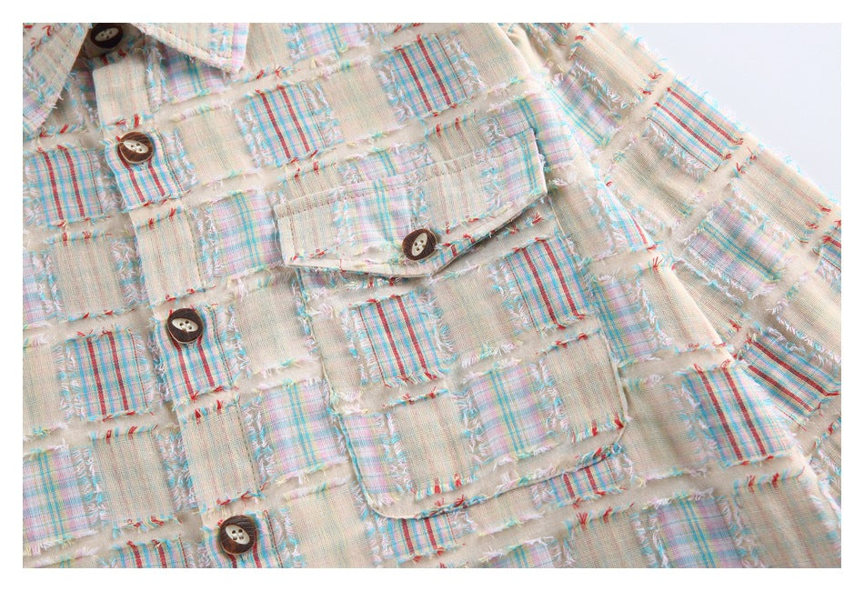 Close-up of the shirt's chest pocket, buttons, and multicolor plaid patchwork with frayed edges.