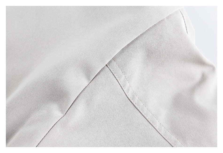 Close-up of overlapping pale gray-beige fabric panels and a stitched seam.