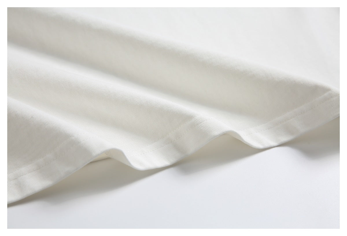 Close-up of the stitched hem on a white garment, draped to show the edge and seam.