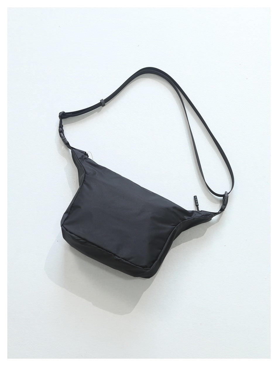 Black shoulder bag with an adjustable long strap, shown against a white background.