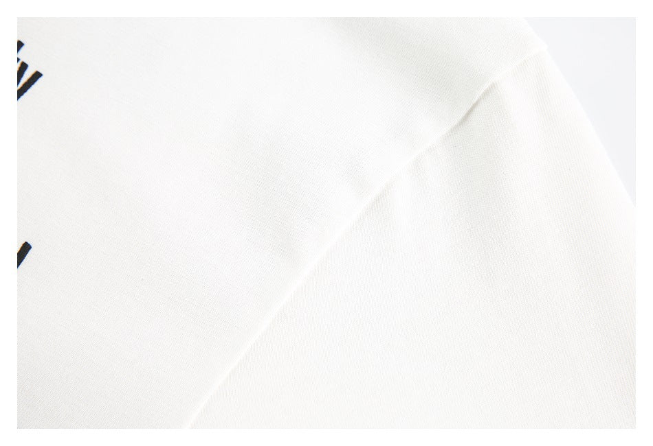 Extreme close-up of white garment fabric with a small cropped portion of black printed artwork at the left edge.