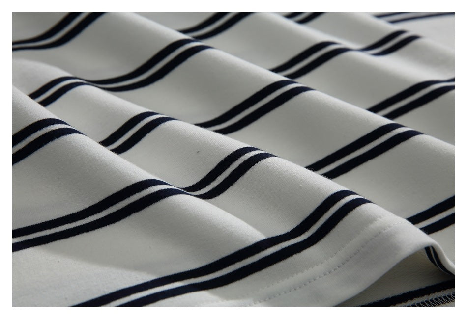 Close-up of draped cream fabric with evenly spaced navy stripes and a stitched edge.