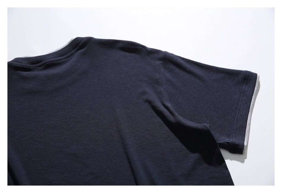 Partial flat-lay view of a dark navy short sleeve and plain body, with gray fabric peeking at the sleeve edge.