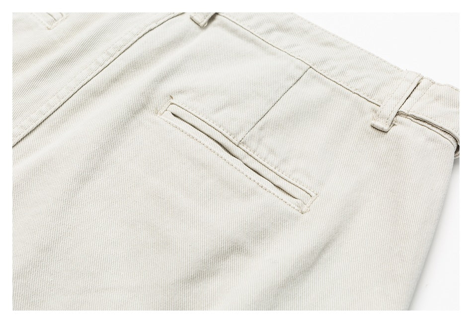 Close-up of off-white trousers showing a narrow welt pocket, waistband, and belt loop.
