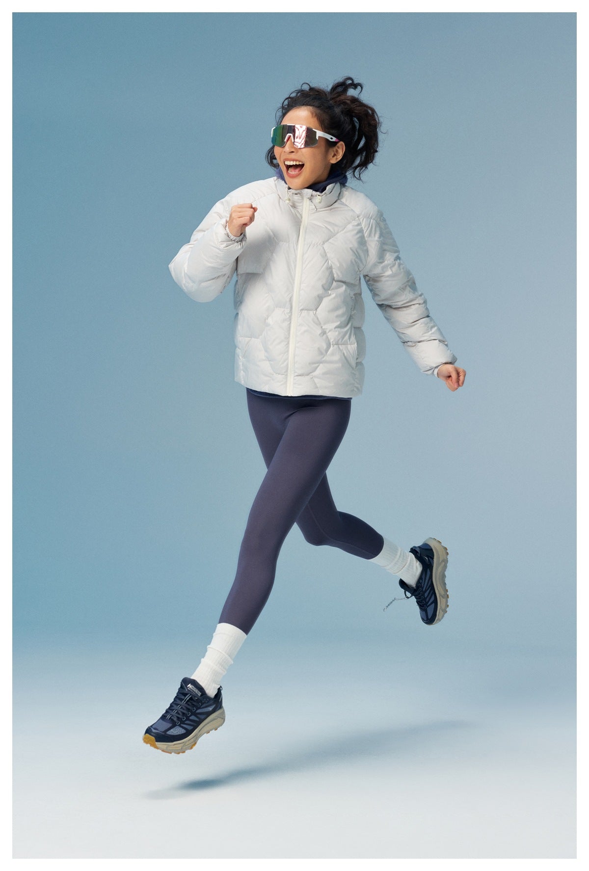 Model in a white quilted jacket and dark leggings, captured mid-run in a full-length view.