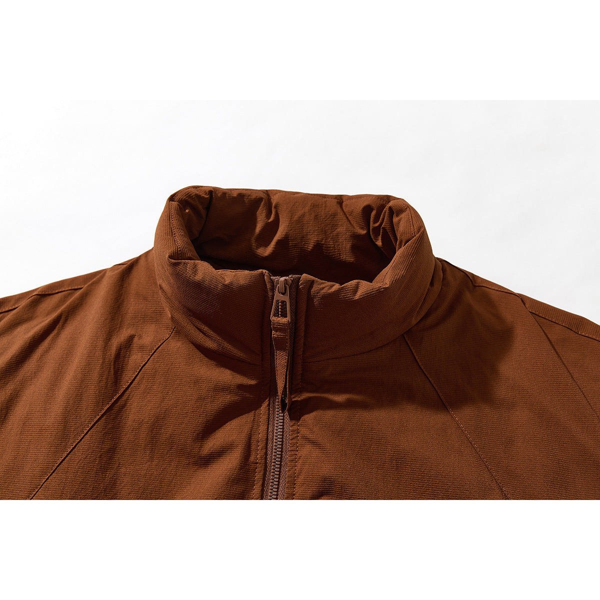 Close-up of a rust-brown jacket's high stand collar, center zipper, and curved shoulder seams.