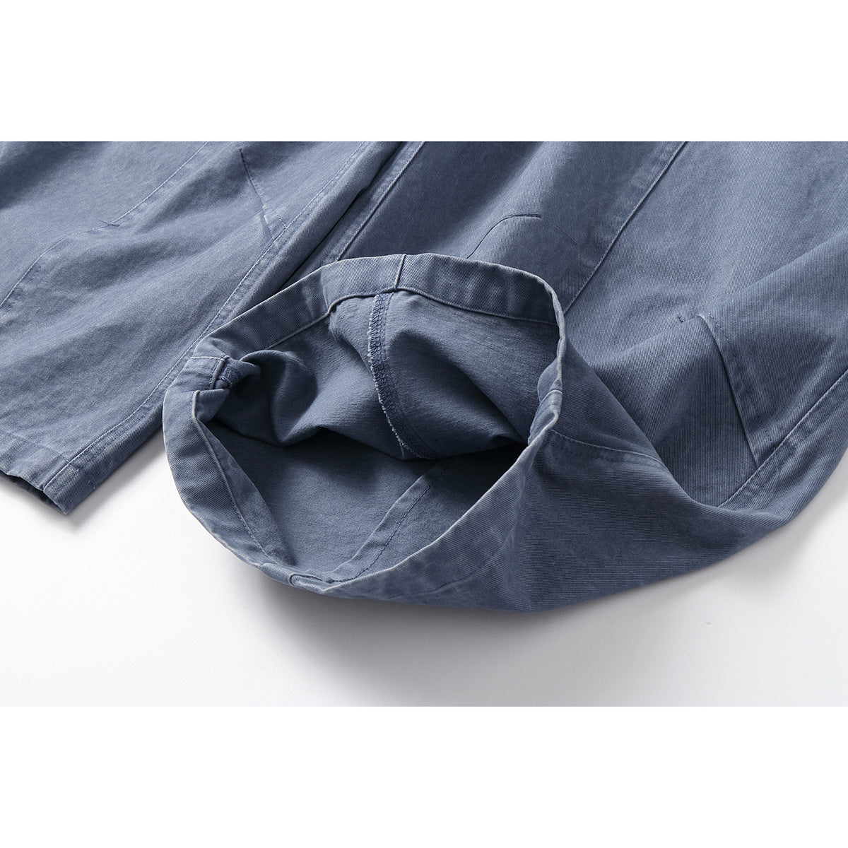 Close-up of the blue-gray trousers' turned-up hem, showing the inside fabric and stitching.