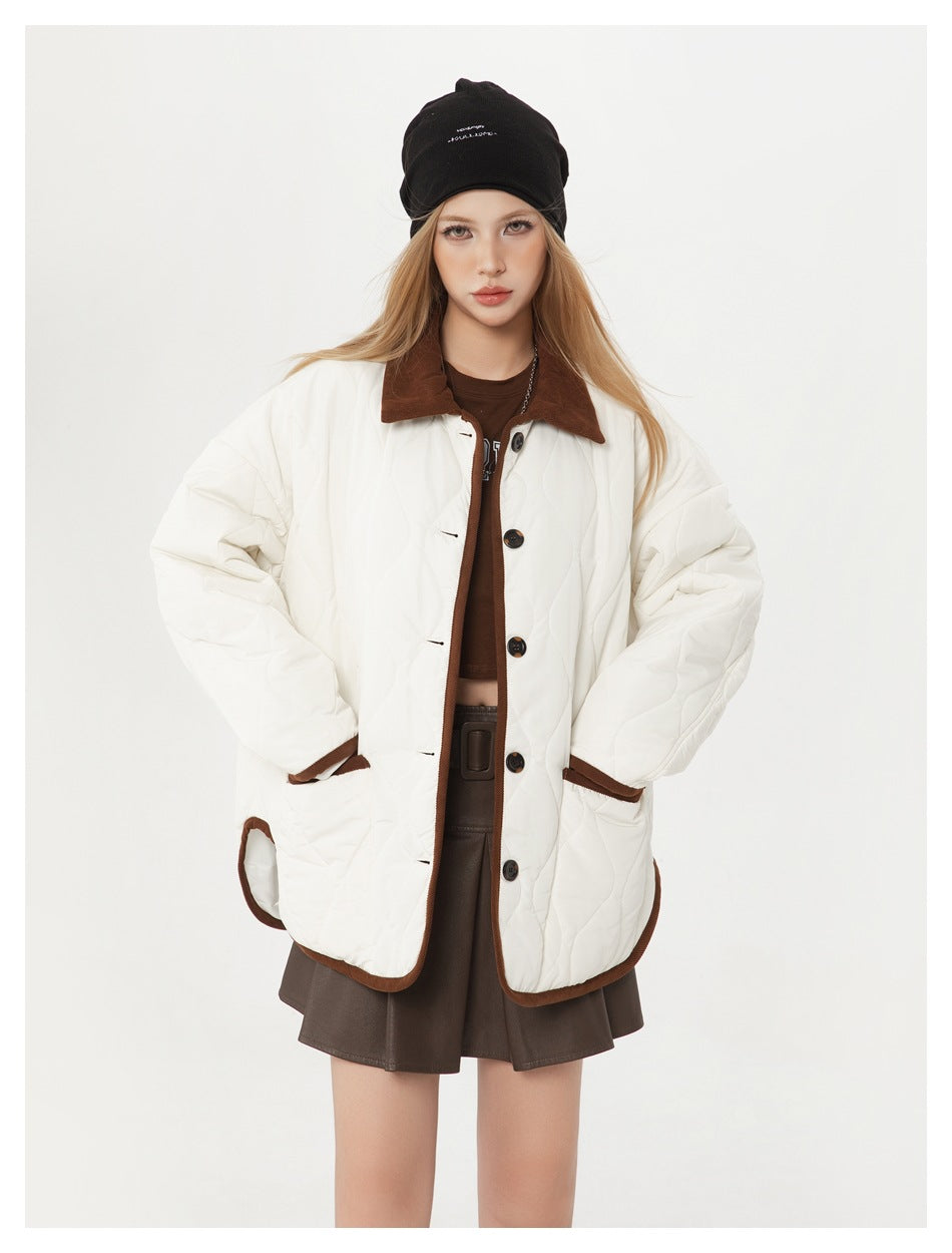 Front view of a model wearing an ivory quilted jacket with brown edging, collar, and dark buttons.