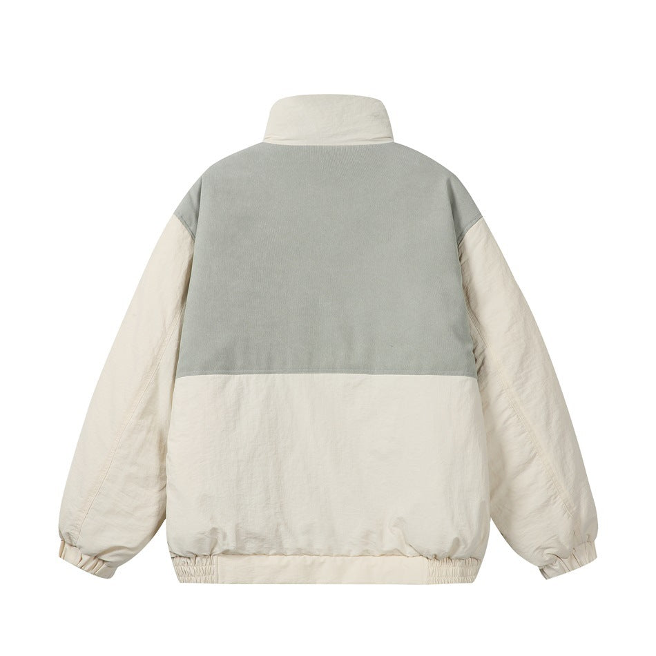 Back view of a color-blocked jacket with a pale sage upper panel, cream lower body and sleeves, and stand collar.