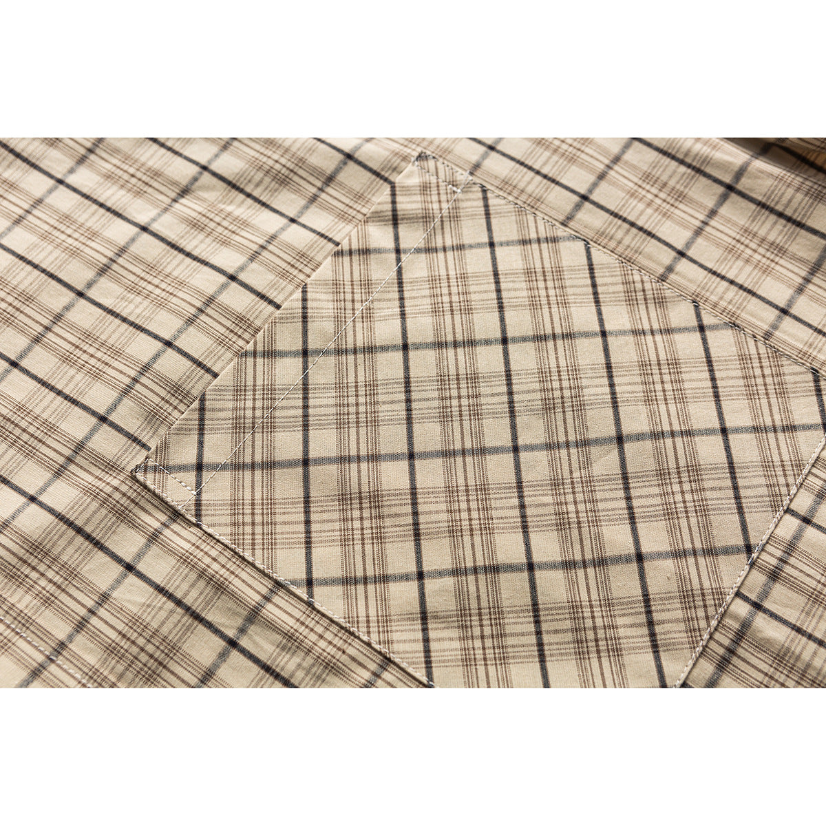 Close-up of a beige plaid shirt's stitched chest pocket and matching plaid pattern.