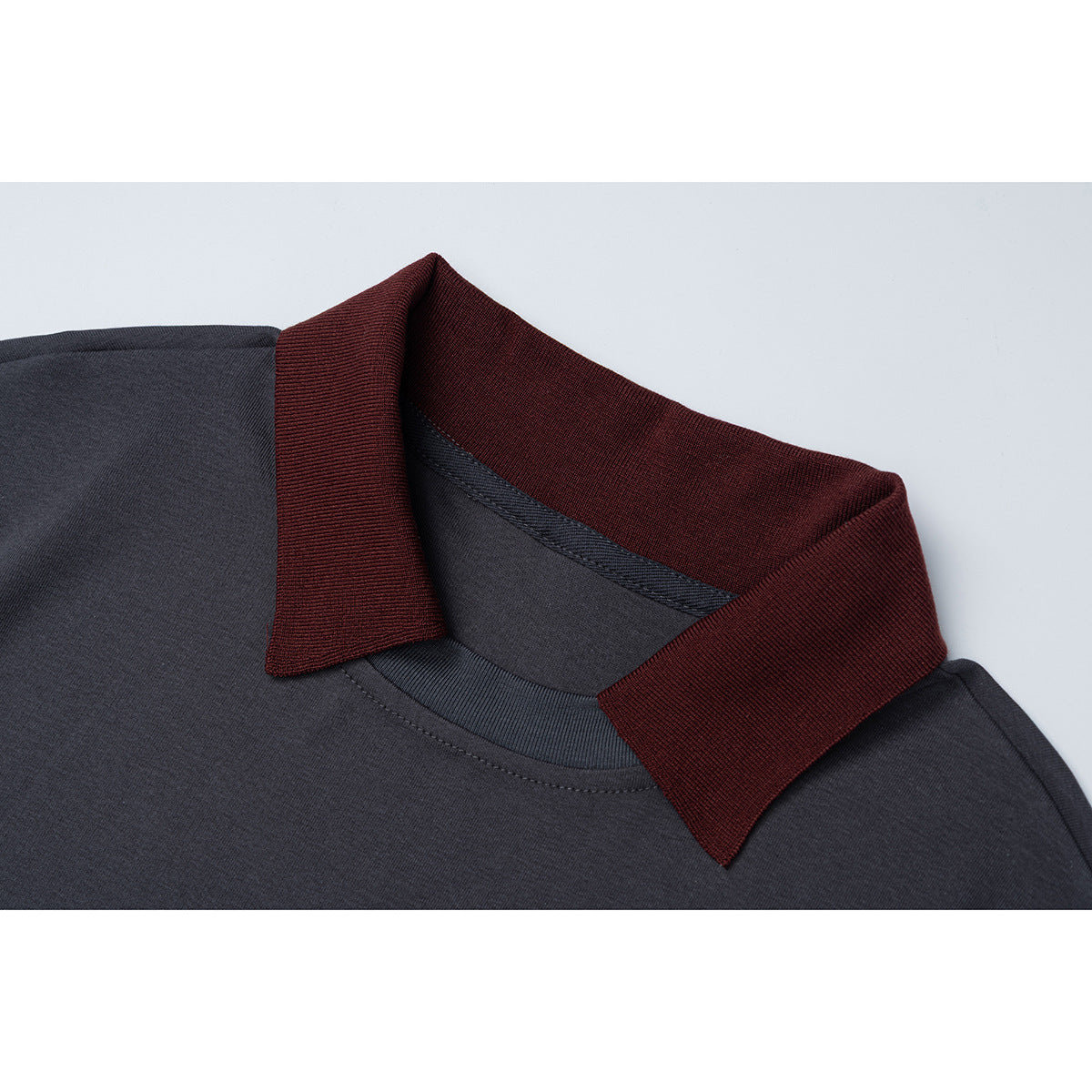 Close-up of a charcoal shirt with a dark burgundy ribbed collar and visible neckline stitching.