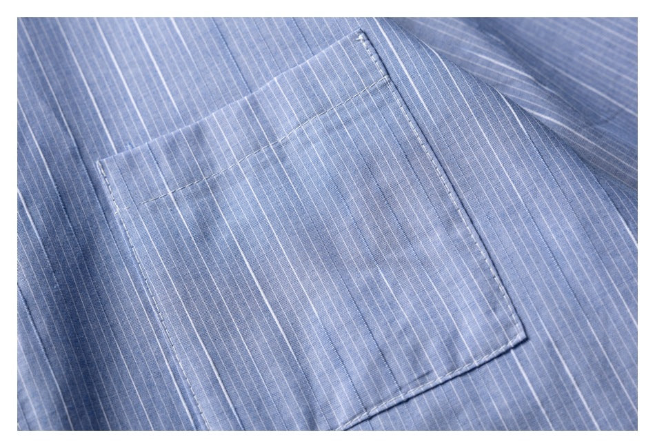 Close-up of a rectangular pocket on blue fabric with fine white pinstripes and visible stitching.