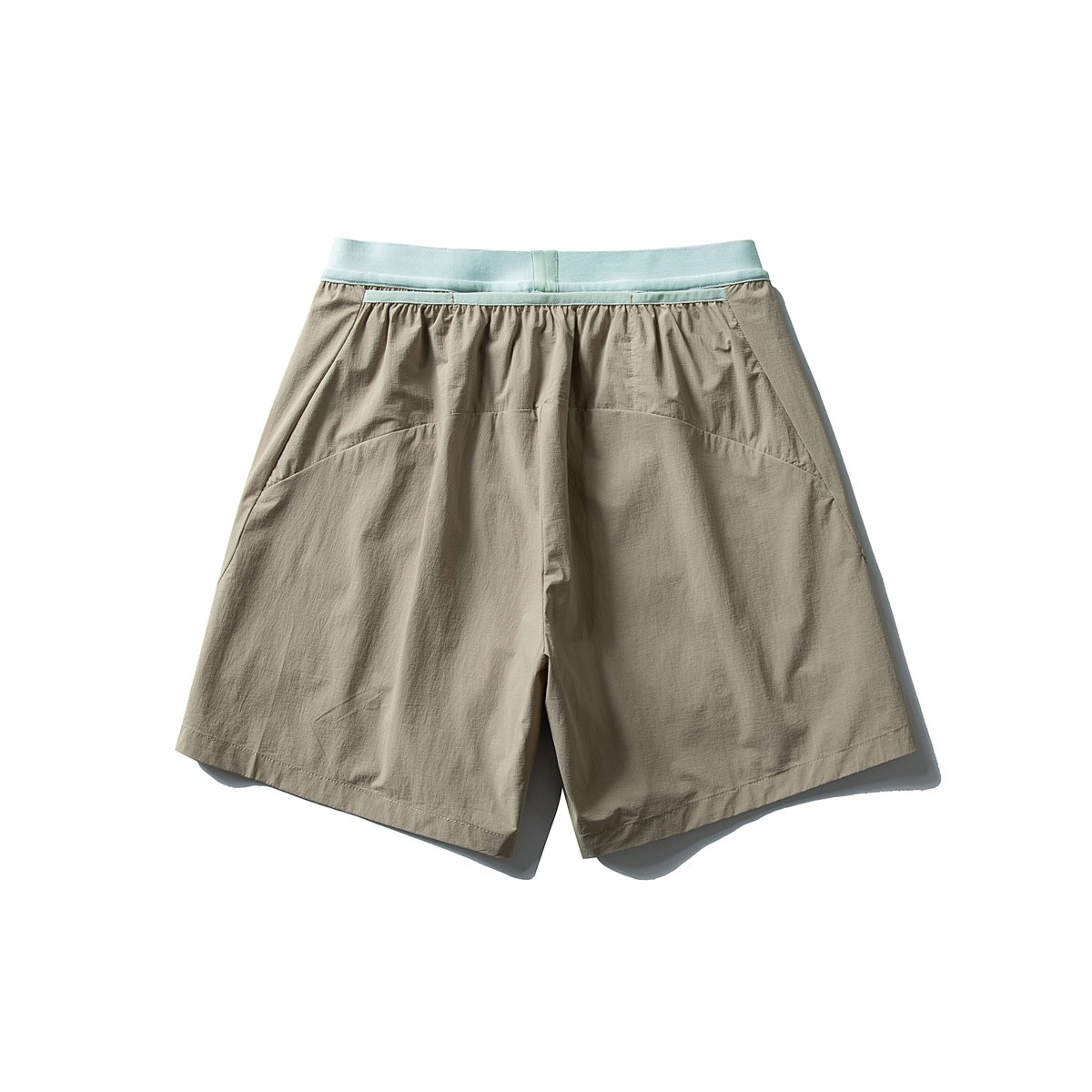 Back view of loose taupe shorts with a pale mint waistband and curved rear panel seams.