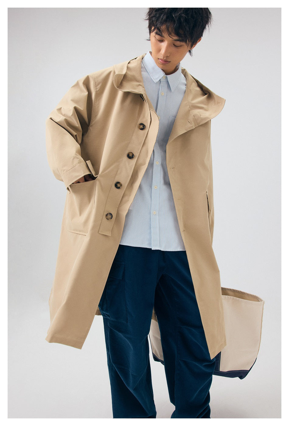 Closer view of a model wearing an open beige hooded coat with large buttons and front pockets.