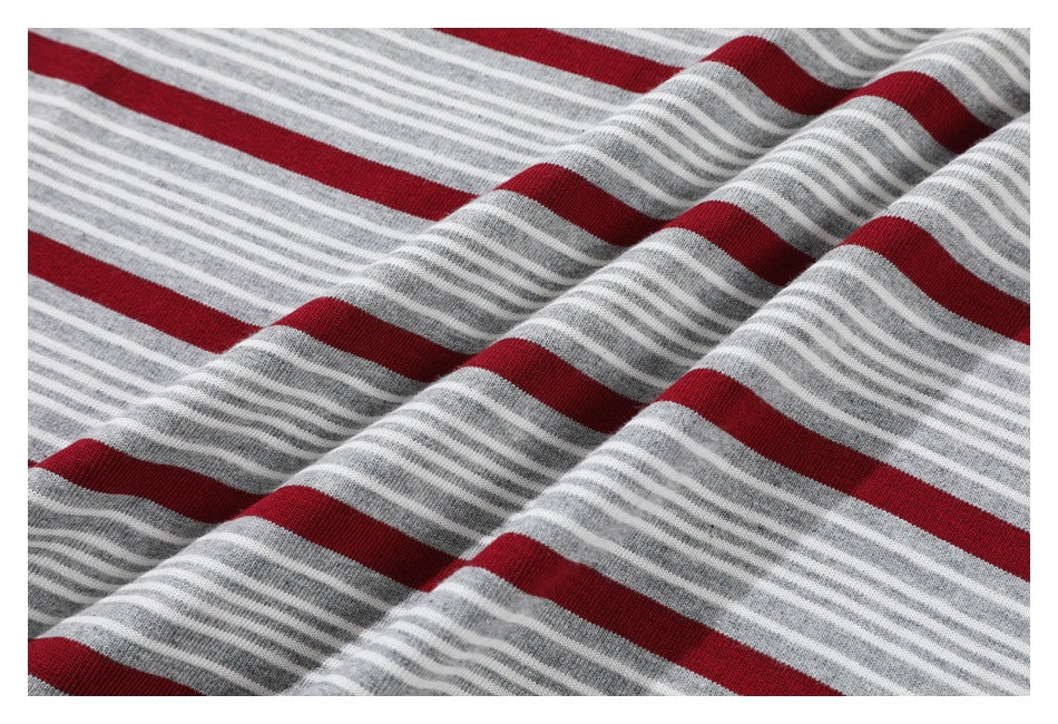Close-up of gray and white narrow stripes alternating with wide red stripes on gathered fabric.