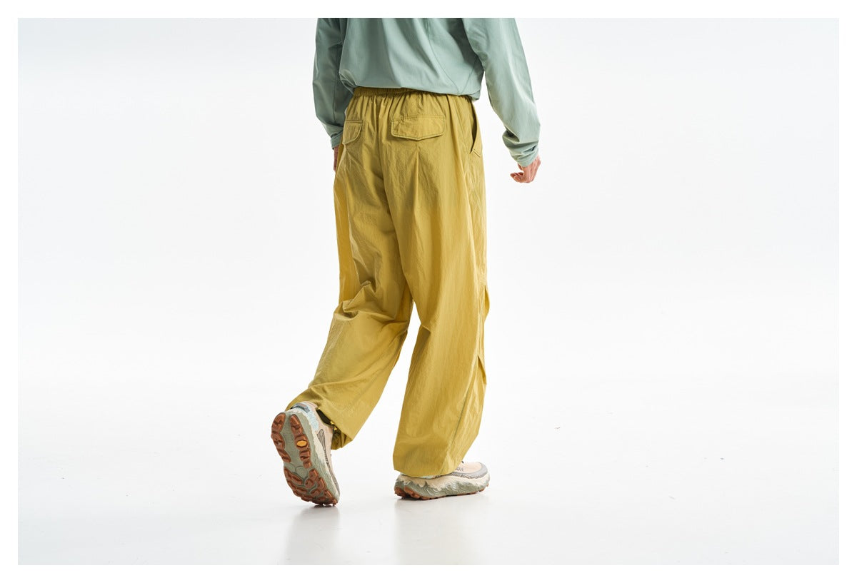 Rear view of a person wearing loose mustard-yellow pants with an elastic waist and back pocket, paired with a pale green top.