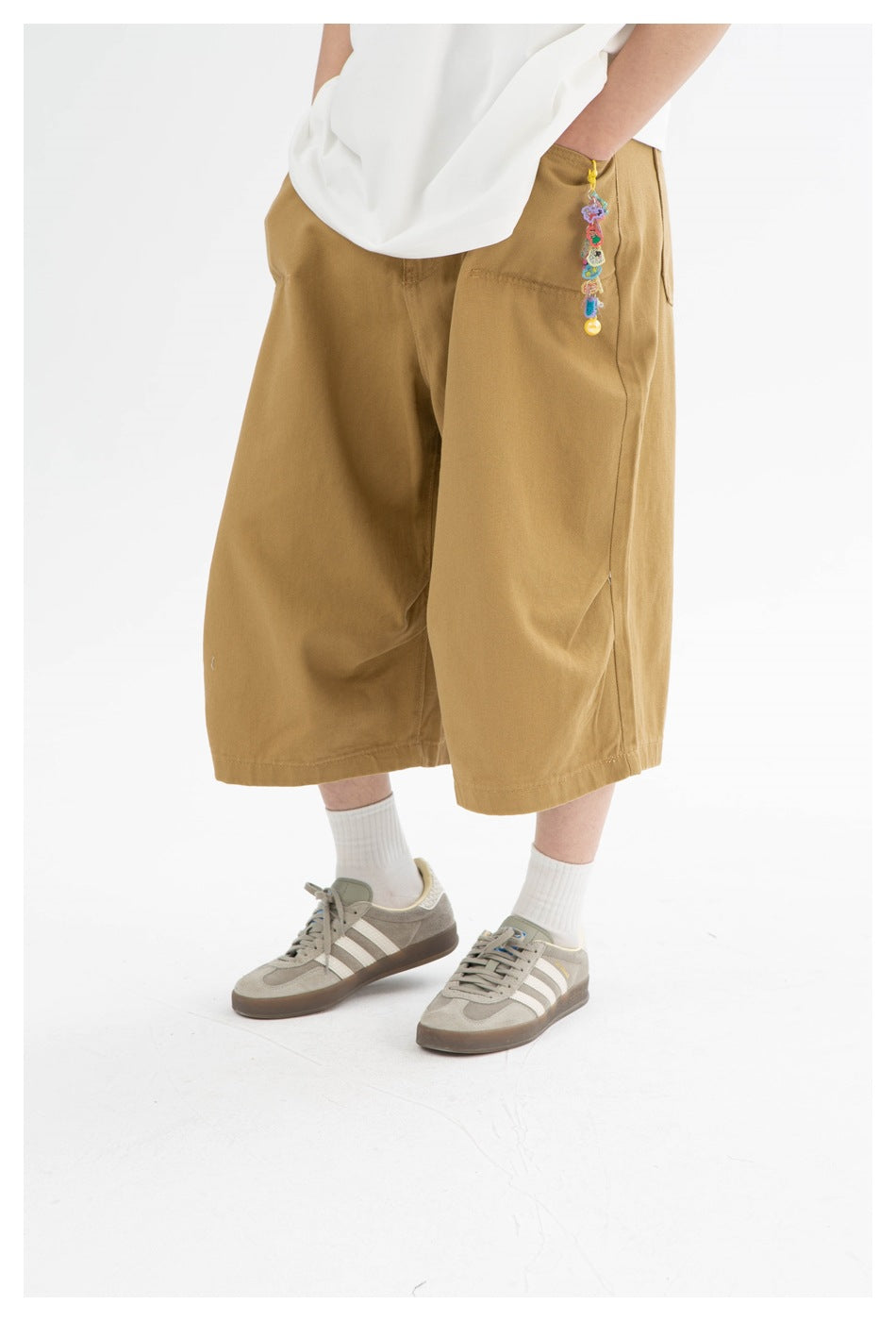 Close-up of tan wide-leg shorts worn with a white top, showing the front pockets and a colorful hanging charm.