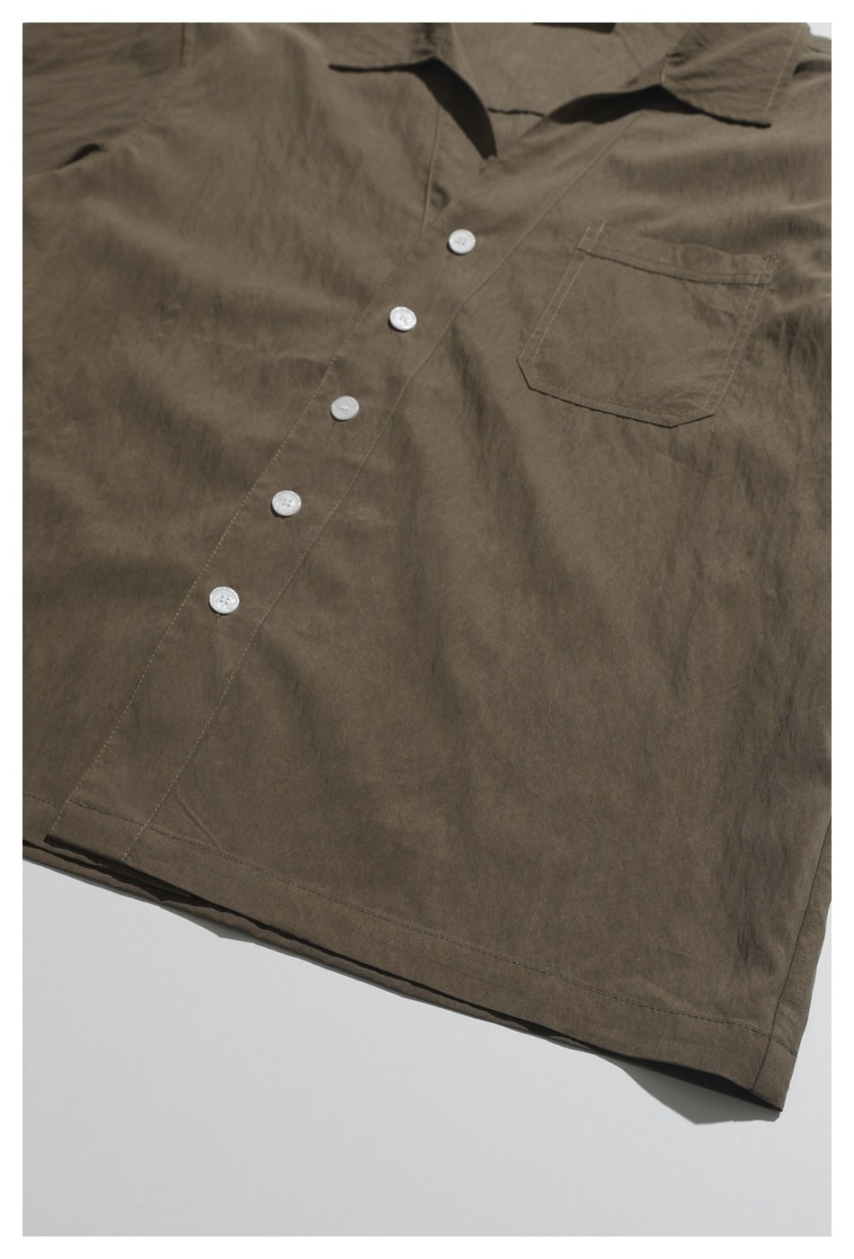 Flat-lay view of a brown short-sleeve button-up shirt with a pointed collar and chest pocket.