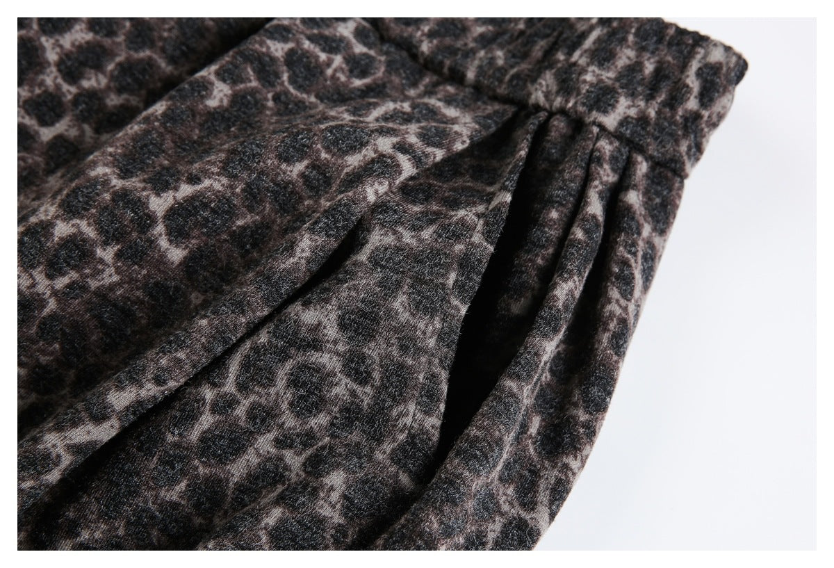 Close-up of a side pocket opening on dark brown and black leopard-print trousers.