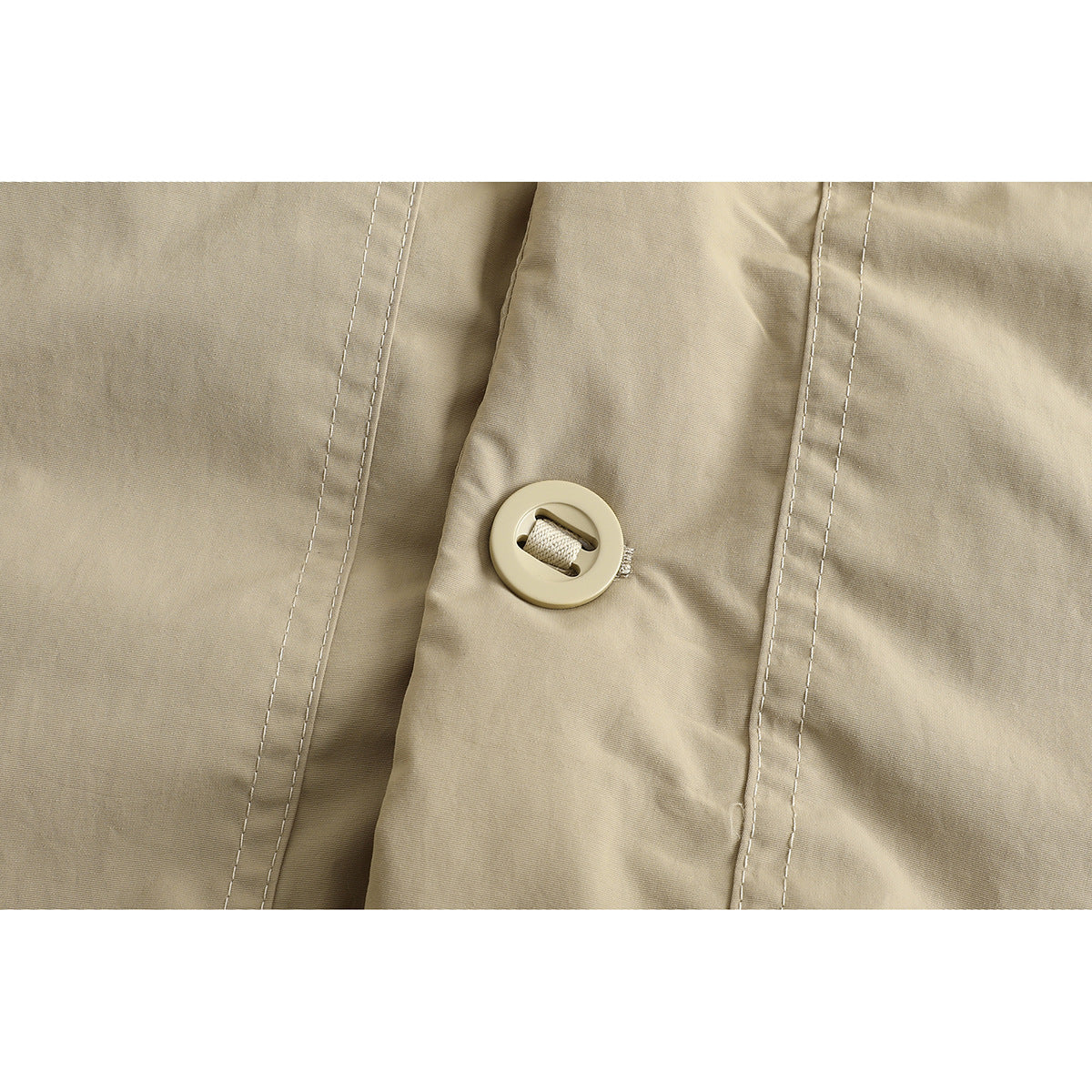 Close-up of a round beige button and stitched placket on the jacket.