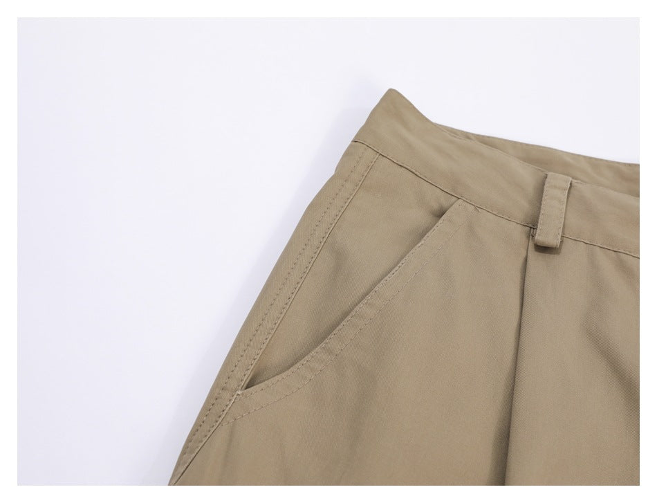 Close-up of khaki trousers showing the waistband, belt loop and slanted front pocket.