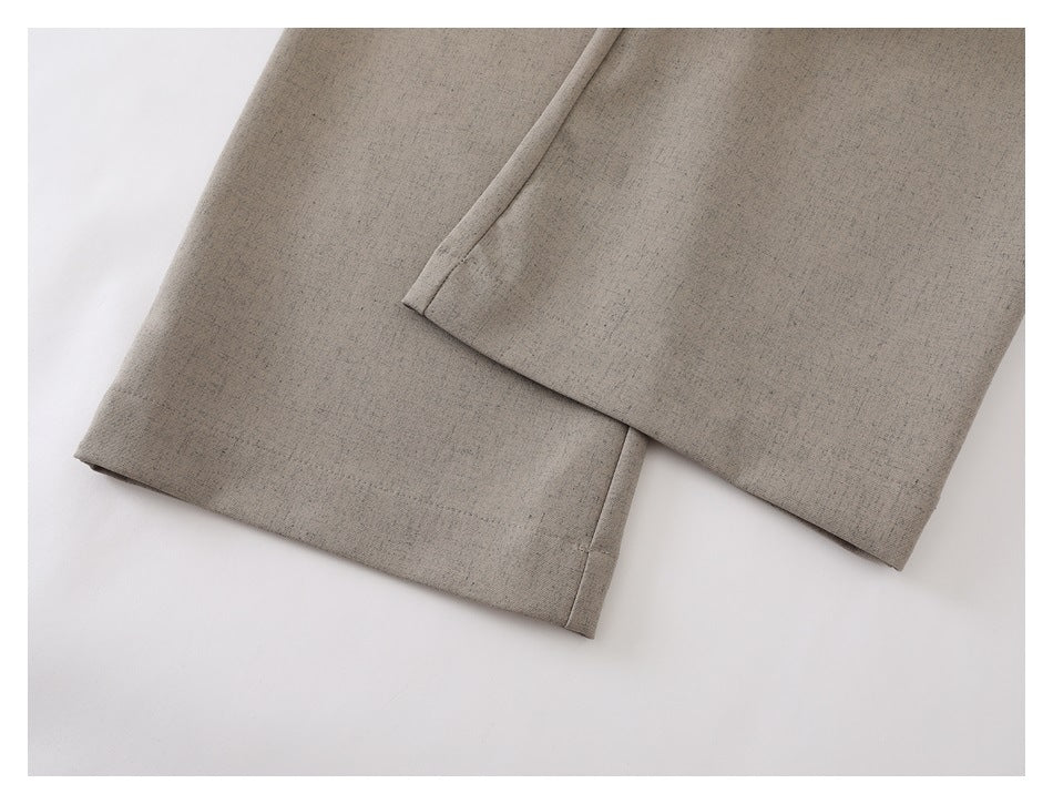 Close-up of the straight hems on beige-gray trouser legs against a white background.