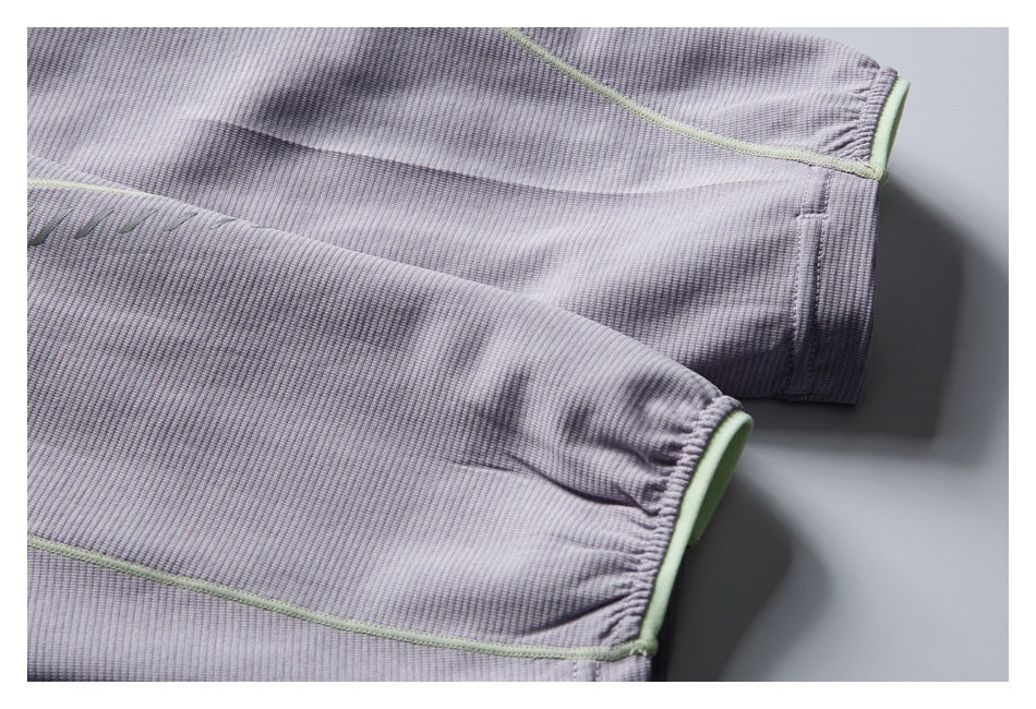 Close-up of two sleeve cuffs on a pale lavender-gray ribbed garment, edged with pale green trim.